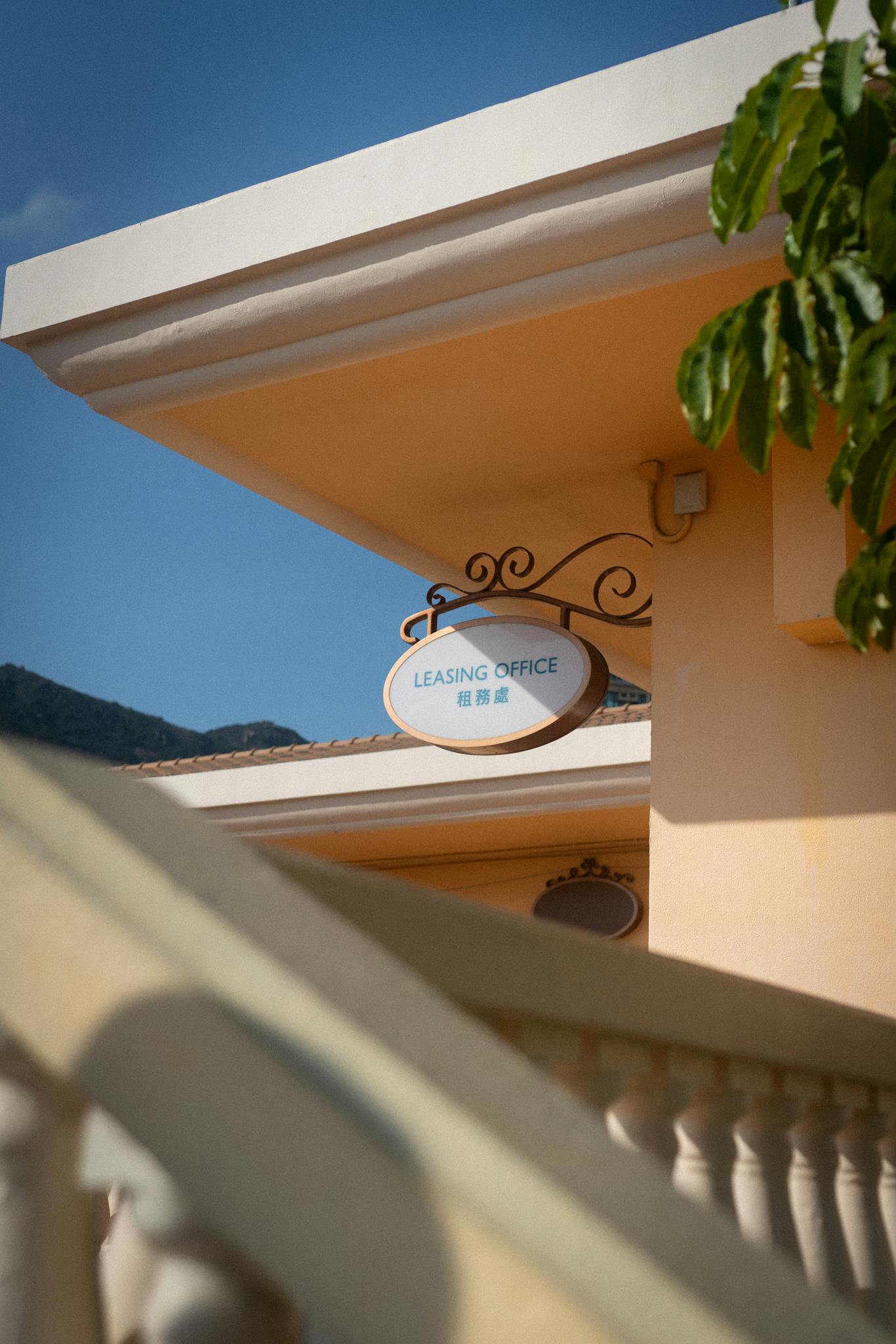 An elegant leasing office sign displayed amidst architectural elements against a clear blue sky.