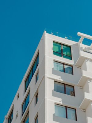A modern white high-rise building against a clear blue sky, architectural design with large windows.