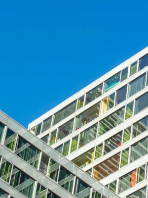 Contemporary glass facade of a modern building in Den Haag against a clear blue sky.