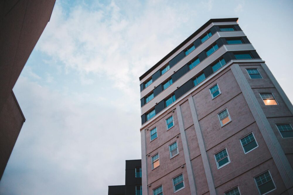 From below of contemporary high rise building with glass brick wall and windows windows under dusky sky
