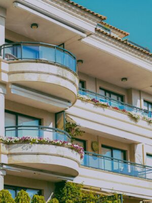Stylish architecture featuring glass balconies and flower decorations on a sunny day.