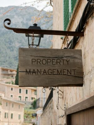 Wooden property management sign in a picturesque European village, featuring charming architecture.